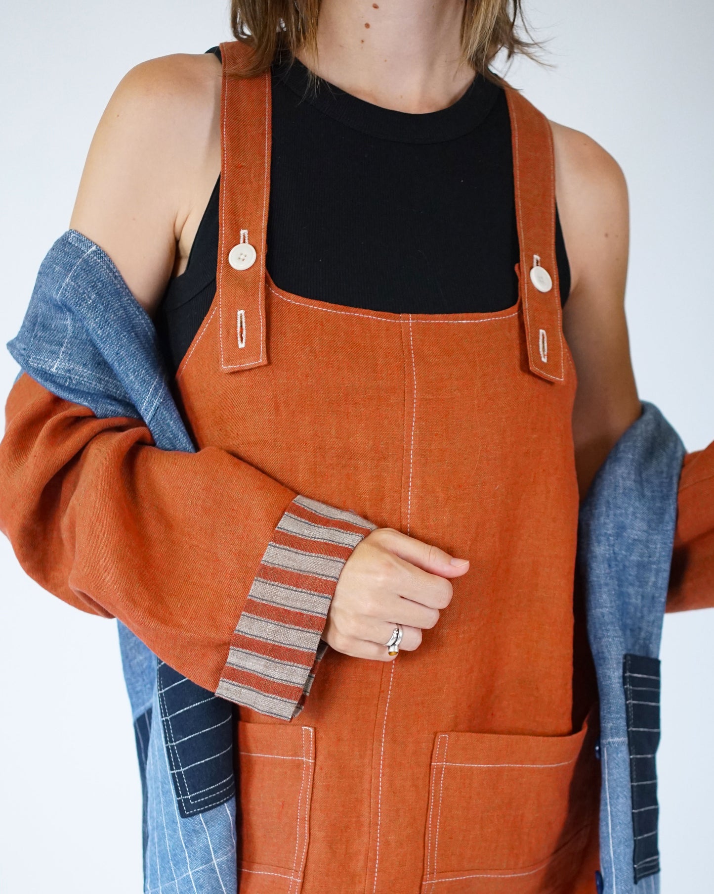 Person wearing orange denim overalls with a plain background