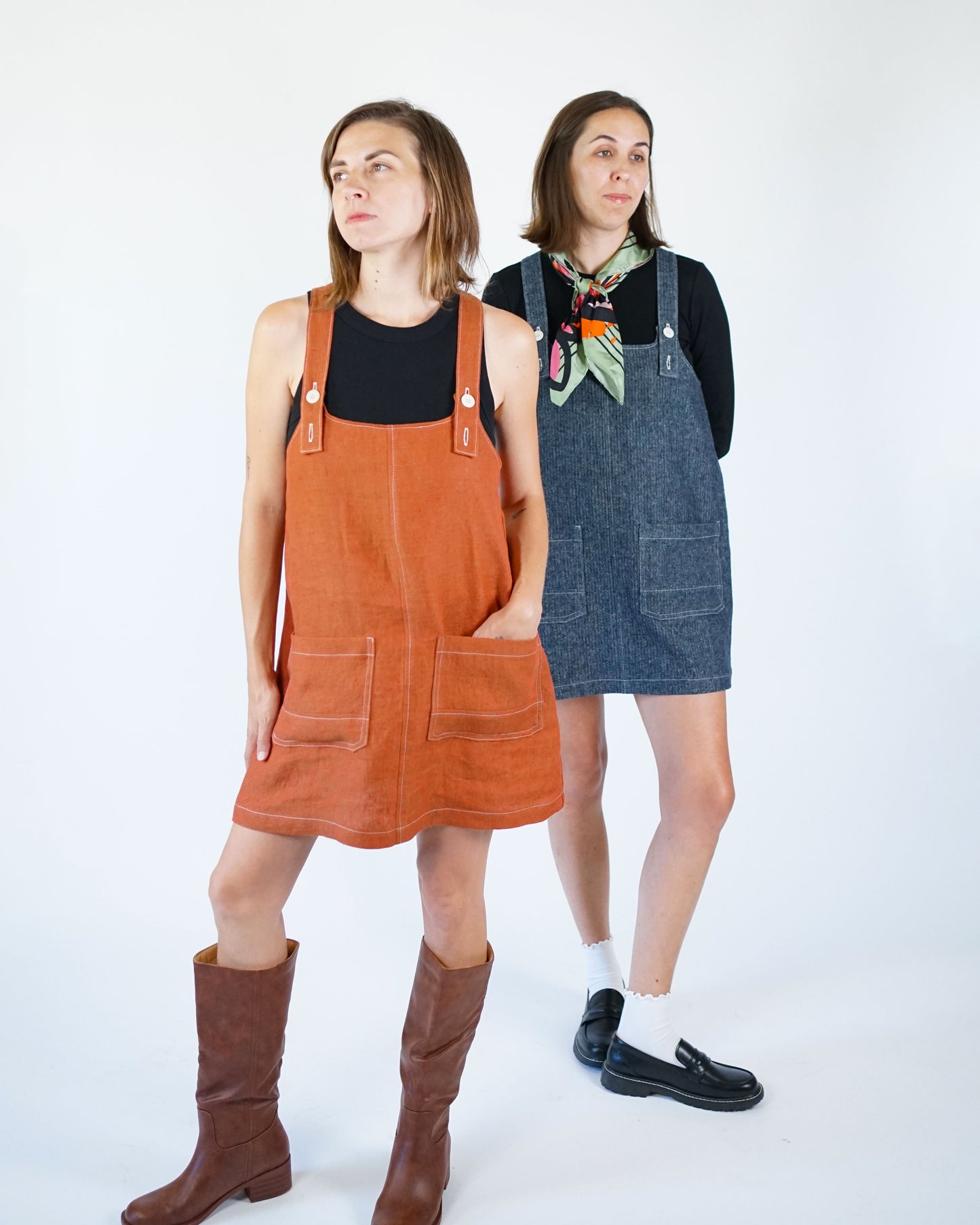 Two women wearing denim and orange overalls against a white background