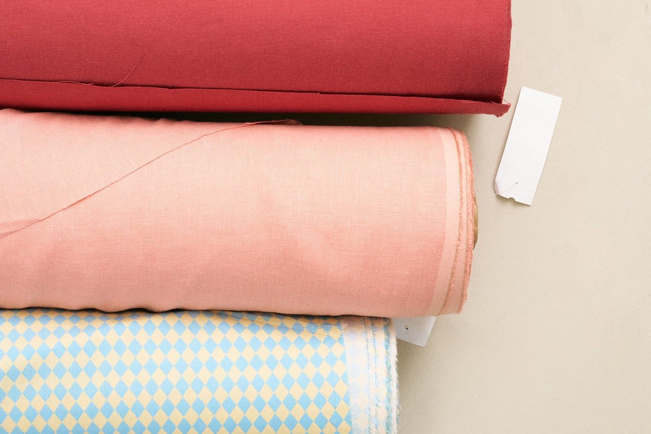 Rolls of fabric in various colors stacked on a light surface