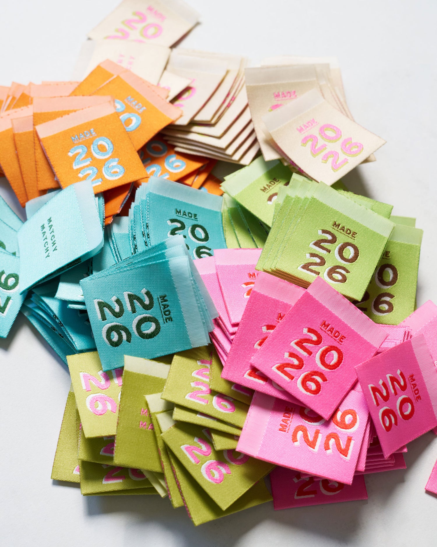 Colorful small garment labels with '2026' text on a white background
