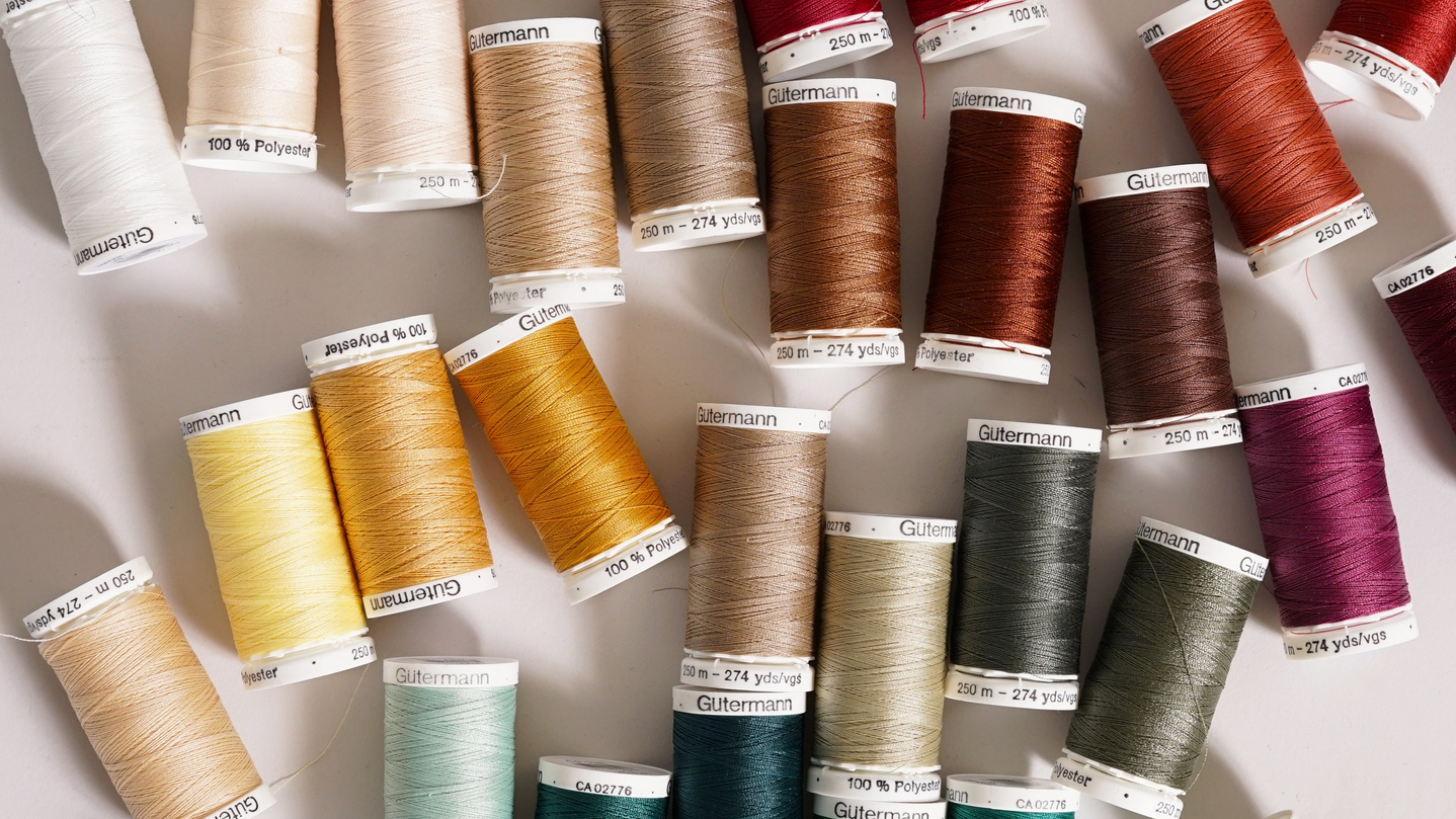 Assorted spools of thread in various colors on a white background