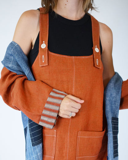 Person wearing orange denim overalls with a plain background