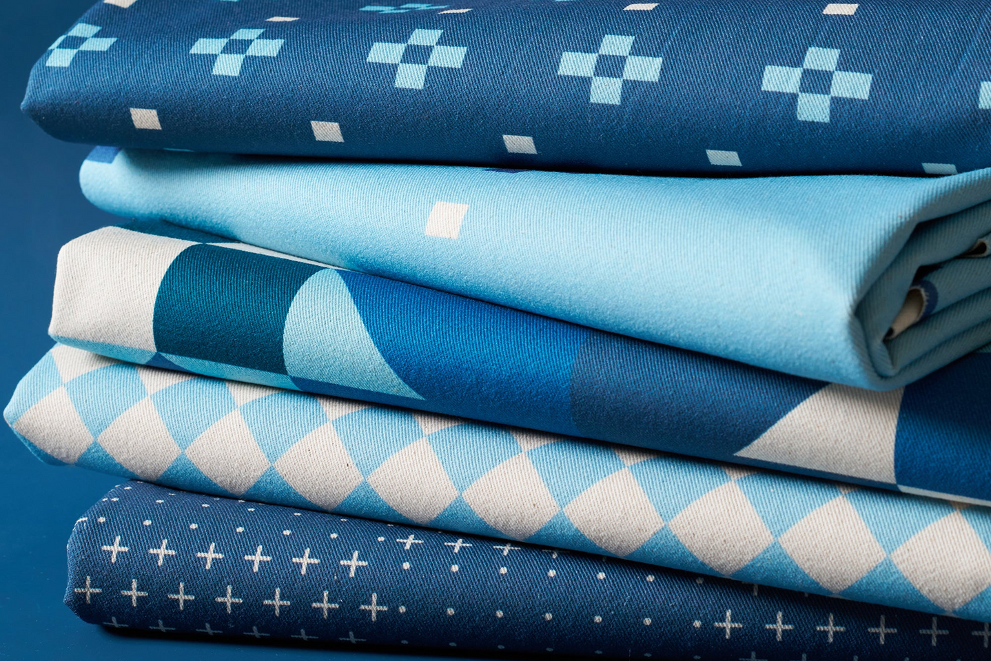 Stack of folded fabric with blue and white patterns on a blue background