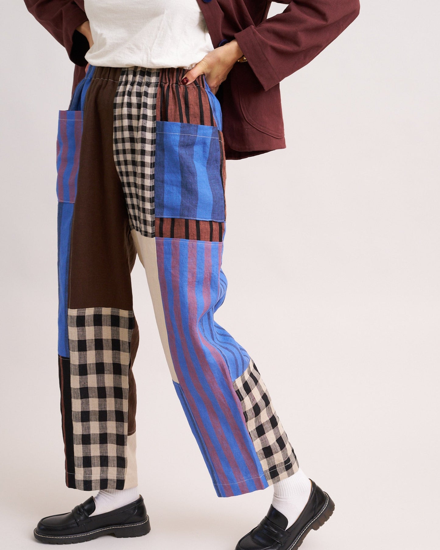 Person wearing patchwork pants with blue, brown, and plaid patterns on a white background